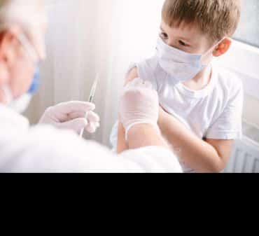 A child wearing a mask receives a vaccination. Image credit: Shutterstock. 