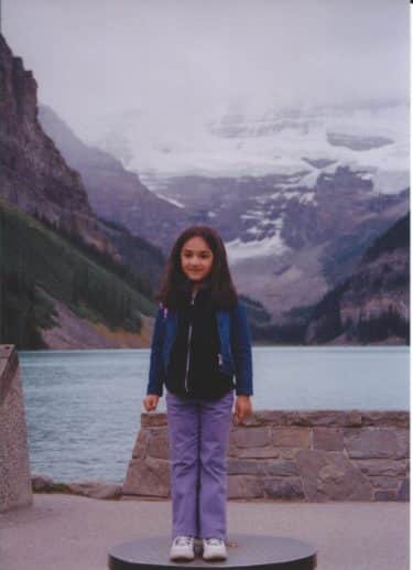 Misha Patel as a child, aged 6, standing in front of an ice water lake in Jasper National Park, Canada