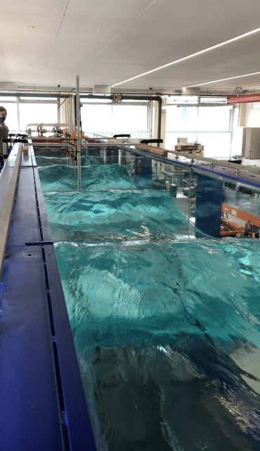 An indoor wave tank in operation, generating waves across the surface of the water. 