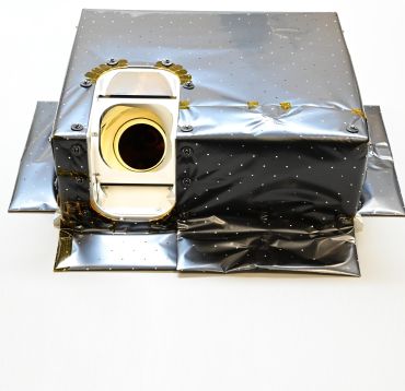 A small box with a camera lens wrapped in a shiny blanket.