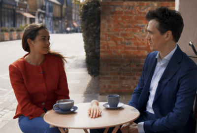 Eugenia and Fabian talk over a cup of coffee. Featured website image for the video "Code-Based Colleagues".