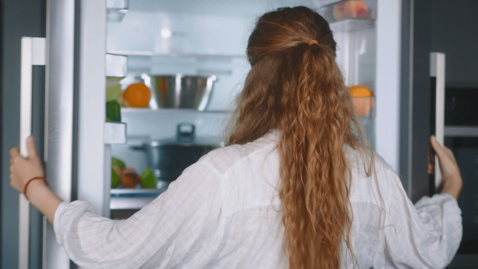 A woman opens a fridge. Featured image for the video "The Brains Behind Your Breakfast".