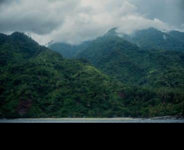 Two hills rise dramatically from the shoreline, covered in thick jungle.