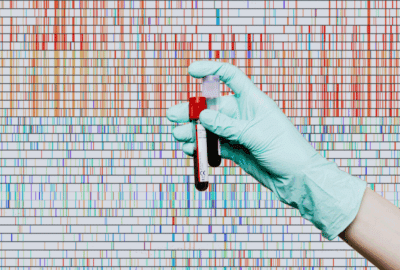 Visualisation of a genome sequence (vertical stripes of blue and red) overlaid by a gloved hand holding two tubes of blood.