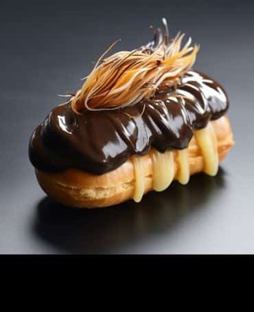 AI-generated image showing a chocolate éclair with a candyfloss topping styled to look like hair.