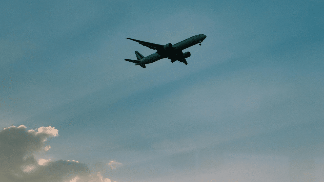 Silhouette of an aeroplane taking off, against a blue sky.