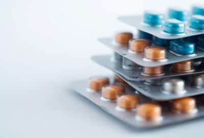 Stack of blister packs, containing coloured pharmaceuticals. AI-generated image (Lucid Origin).