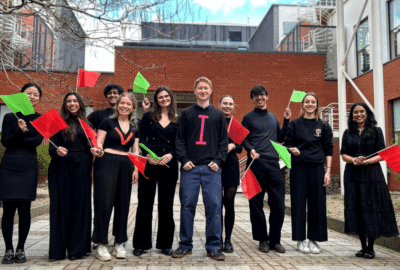 A group of young people dressed in black and holding red and green flags. (The team use these flags to demonstrate the body's immune system response to precancer and cancer vaccines in the video).